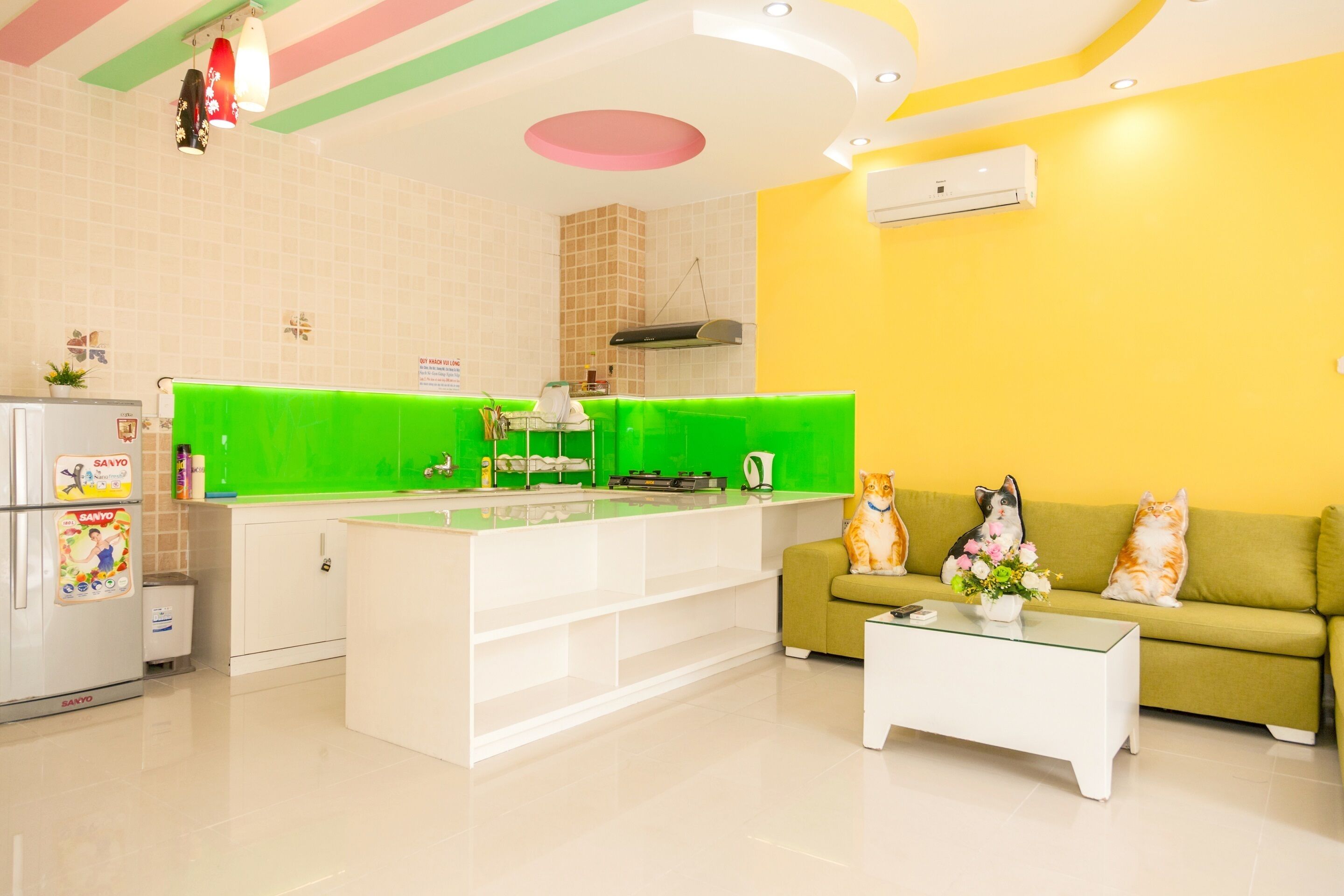A modern kitchen with a green island, white cabinets, and a yellow accent wall.