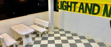 Un piso a cuadros, dos bancos blancos y una pared con el texto "LIGHT AND N".