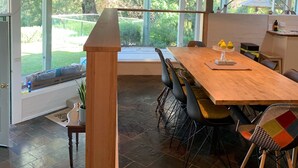 Un vaste espace dédié à la salle à manger, avec une longue table en bois, des chaises modernes et un éclairage suspendu.