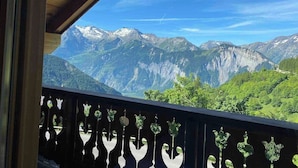 Un balcó amb vista a muntanyes nevades i vegetació exuberant.