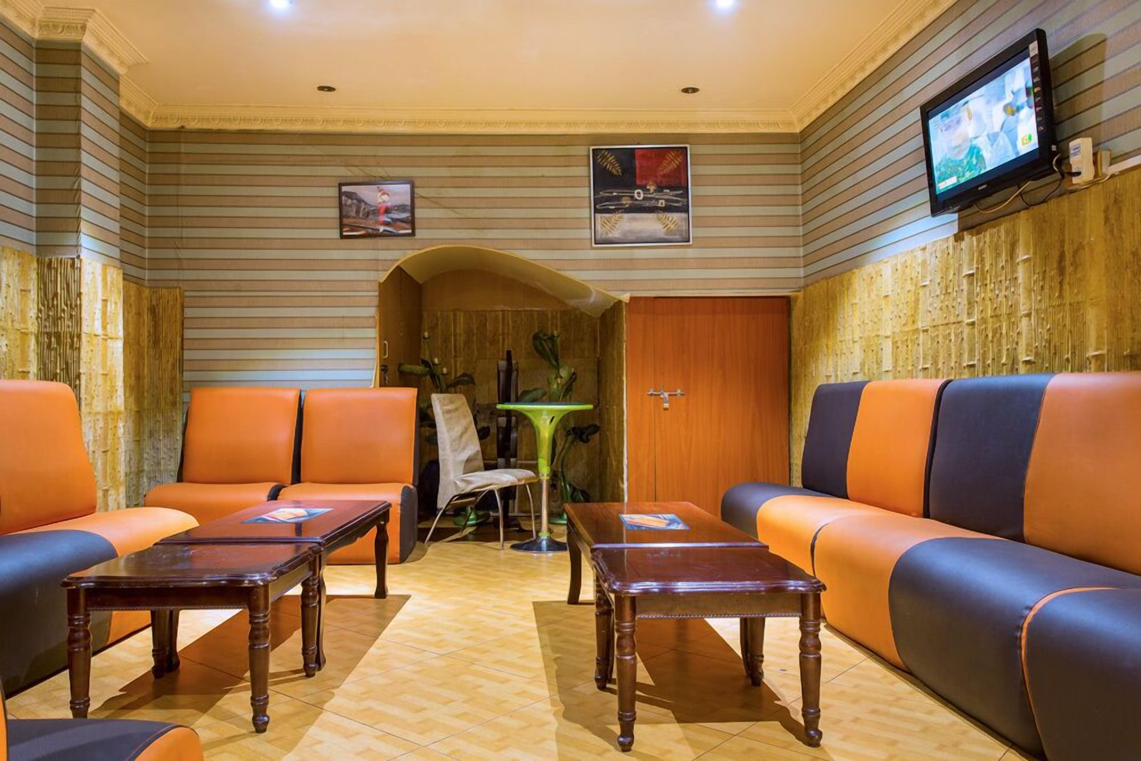 Un hall con un sofá, sillas, una mesa y un televisor.