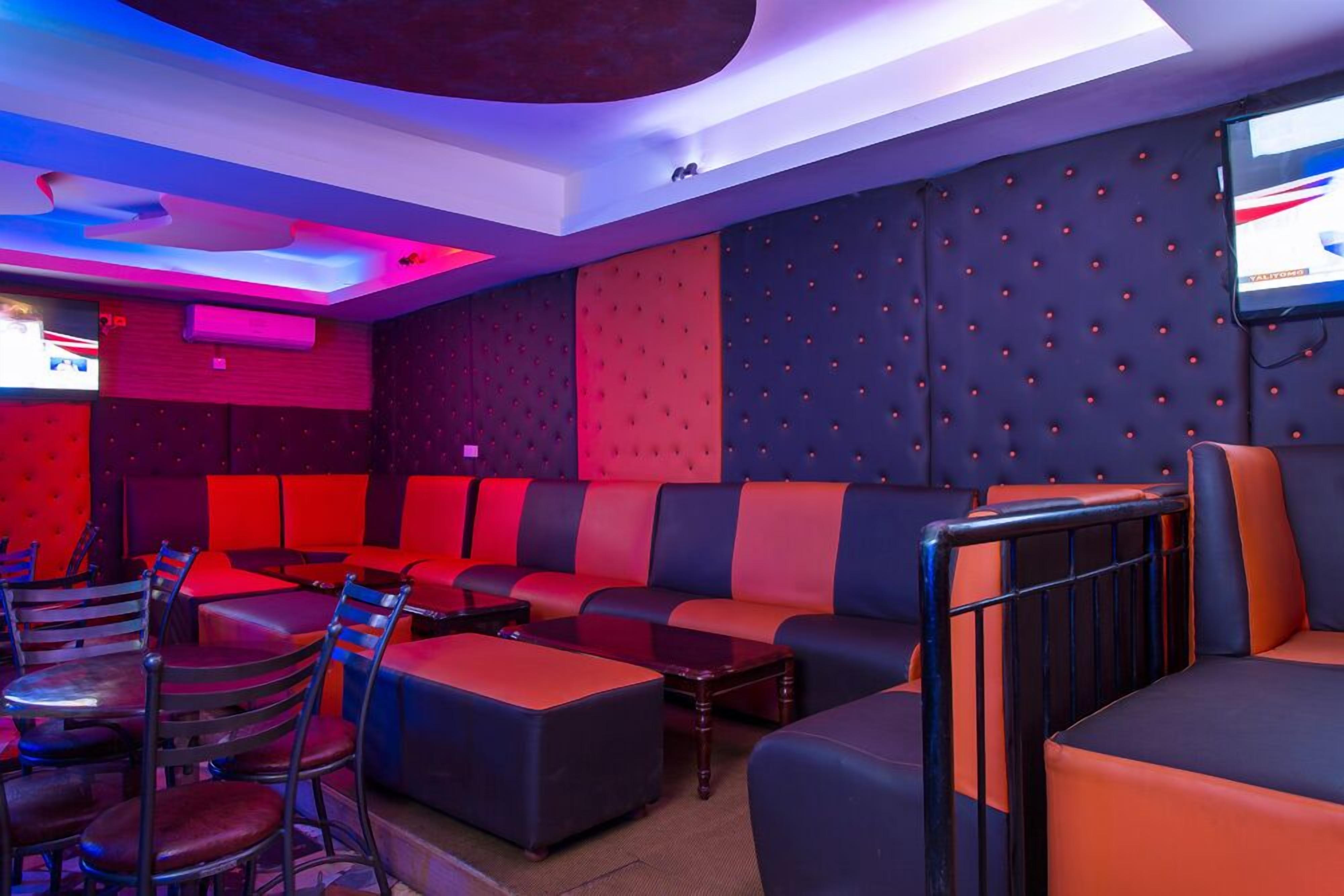 A modern lounge area with red and black seating, a flat-screen TV, and a ceiling with a unique design.