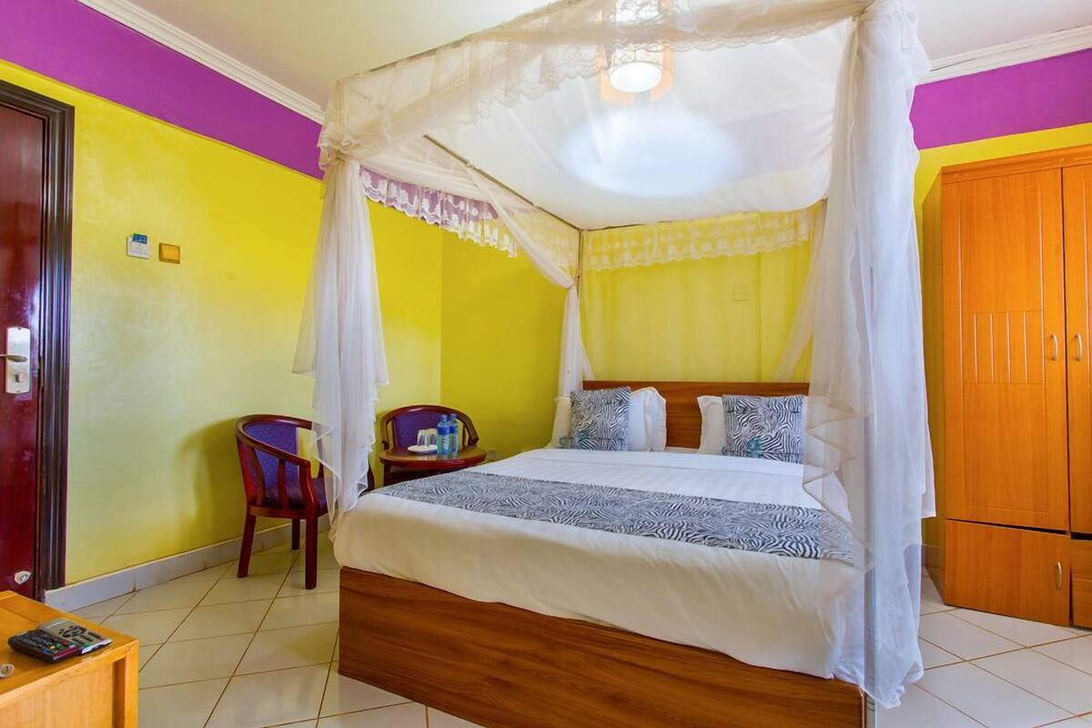 Una habitación con cama, una silla, un armario de madera y una mesita.