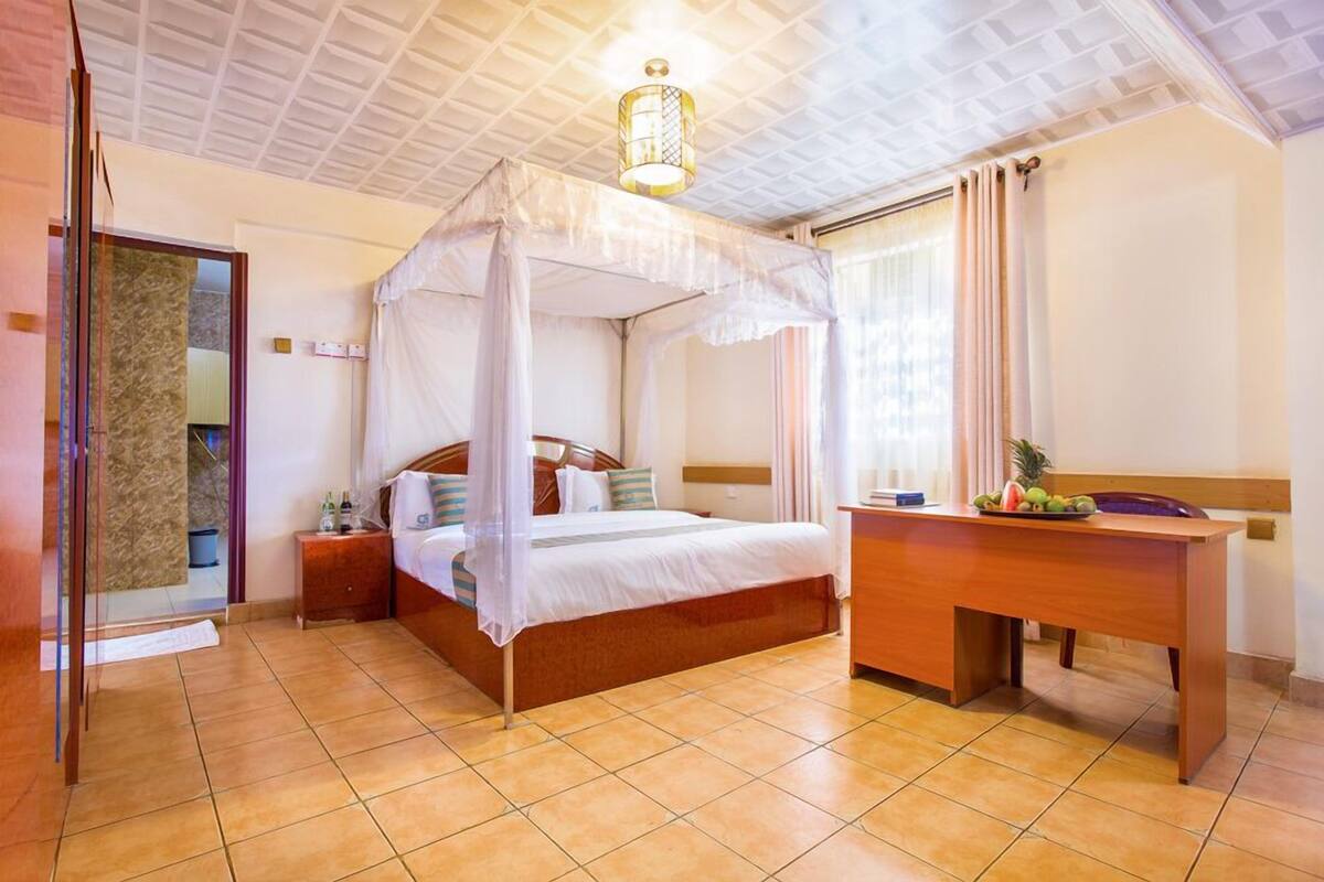 Un dormitorio con una cama con dosel, un escritorio de madera y una mesita de noche.