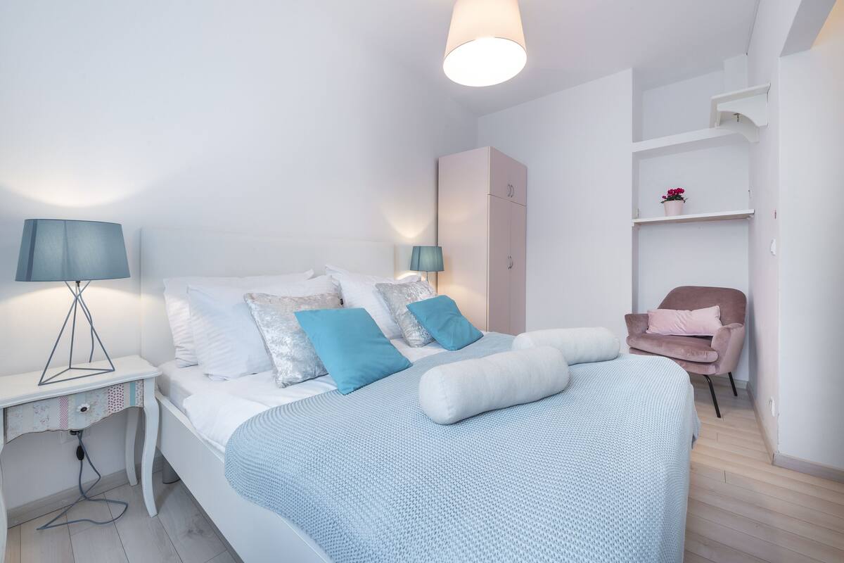 A neatly arranged bedroom with a bed, bedside tables, a wardrobe, and a chair.