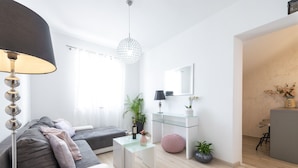 A modern living room with a sofa, a glass coffee table, a lamp, and a hanging light fixture. - Villa Boro 2 (Dubrovnik)