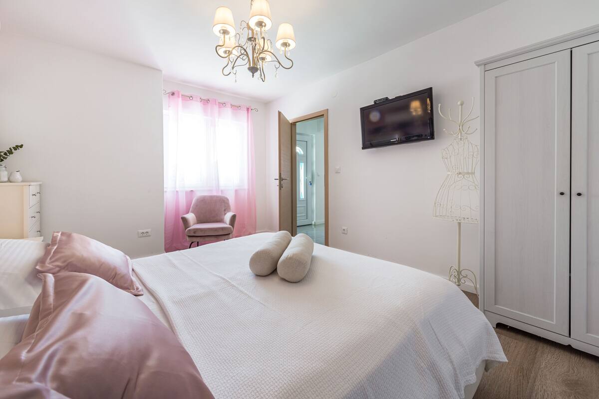 A bedroom with a bed, a TV, a wardrobe, and a chair.
