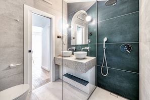 A modern bathroom with a glass-enclosed shower, a vanity with two sinks, and a toilet.