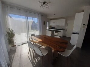 A modern kitchen with white cabinets, a wooden dining table, and a water dispenser.