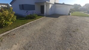 A modern two-story house with a gravel driveway and a small garden with purple flowers. - Beautiful new contemporary house 2 min walk from the beaches of Cabellou (Concarneau)