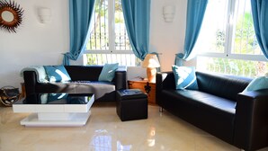 A modern living room with a black leather sofa, a white coffee table, and a blue-toned decor. - Villa Bienestar Jávea with pool (Xàbia)