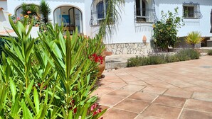 A white building with terracotta roof tiles, stone accents, and multiple windows with wrought iron grilles. - Villa Bienestar Jávea with pool (Xàbia)