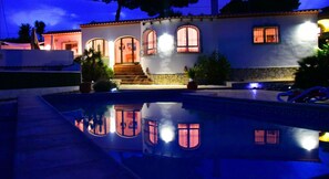 Uma casa com piscina, escadaria e entrada bem iluminada.