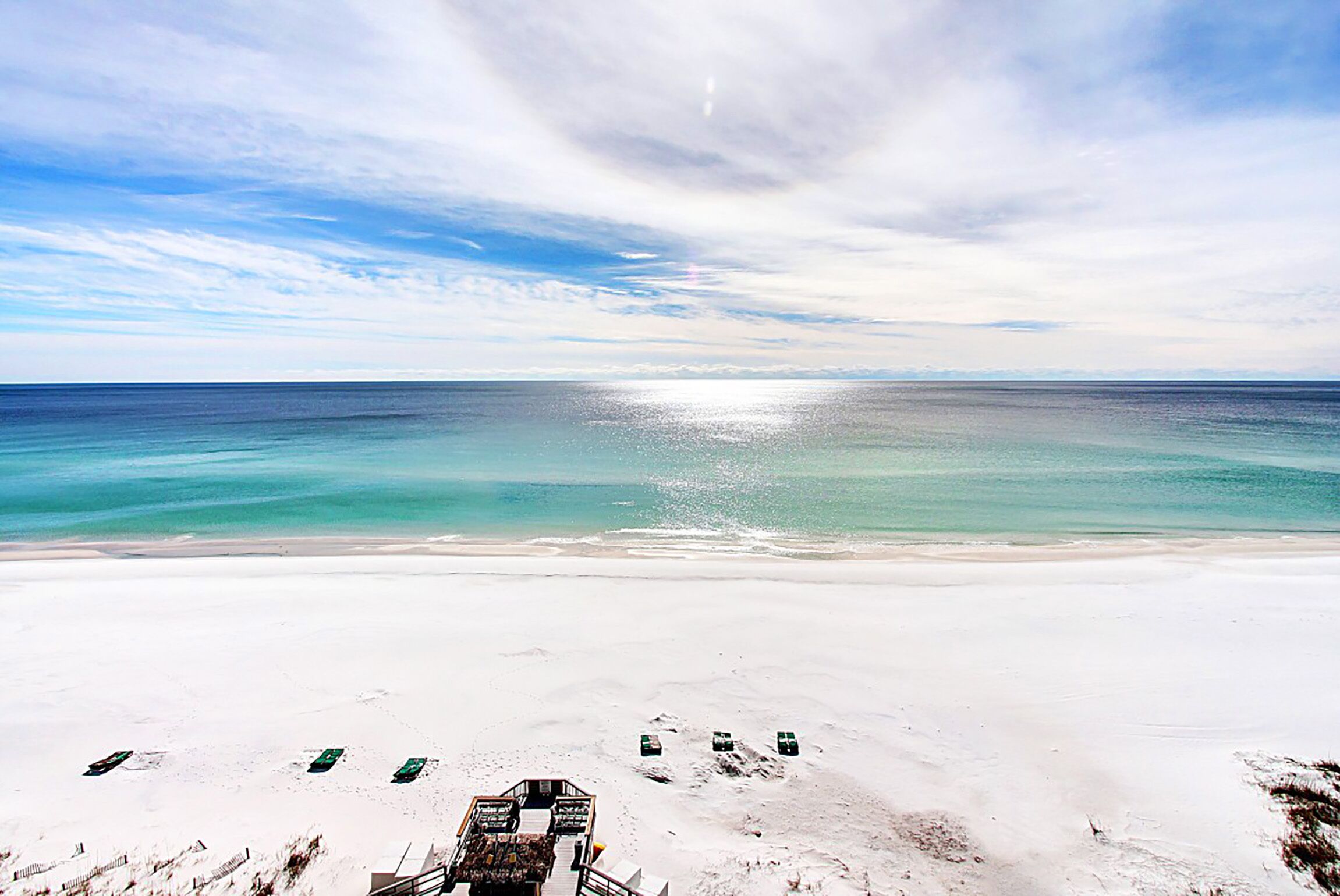 A beach with a clear view of the ocean and a sandy area with a few structures.