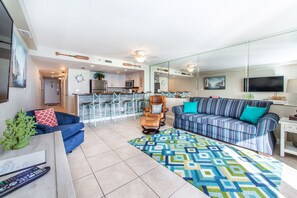 A modern living room with a sofa, armchair, and a patterned rug.