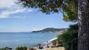Une vue sur la côte, avec une plage, des gens qui se détendent et un ciel dégagé.