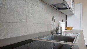 Une cuisine moderne dotée d’un évier en acier inoxydable, d’un lave-vaisselle Bosch et d’un dosseret de carrelage blanc.