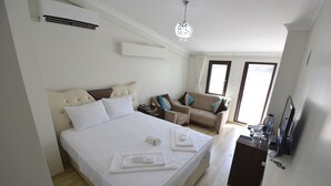 A hotel room with a large bed, a sofa, a desk with a computer, and a TV. - Mavi Deniz Butik Otel (Mudanya)
