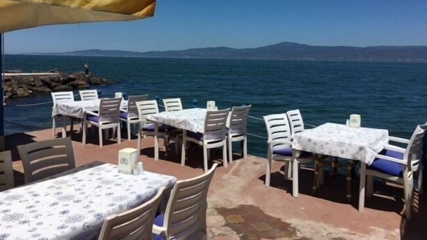 An outdoor seating area with tables and chairs, overlooking a body of water and distant mountains. - Mavi Deniz Butik Otel (Mudanya)