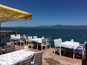An outdoor seating area with tables and chairs, overlooking a body of water and distant mountains. - Mavi Deniz Butik Otel (Mudanya)