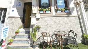The Mavi Deniz Butik Hotel facade with a sign, windows, and outdoor seating. - Mavi Deniz Butik Otel (Mudanya)