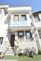 Fachada del Mavi Deniz Butik Hotel con un letrero, ventanas y terraza.
