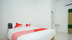 A hotel room with a bed, white walls, a white sink, and a green curtain. - Hotel O Choco 88 Residence (Dringu)