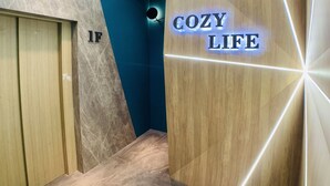 A hallway with a 'COZY LIFE' sign, wooden and marble walls, and a ceiling with linear lighting. - Taichung Wululu (Taichung)