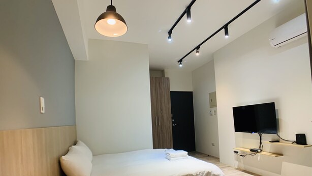 A modern hotel room with a large bed, a flat-screen TV, a bedside table, and a built-in air conditioning unit. - Taichung Wululu (Taichung)