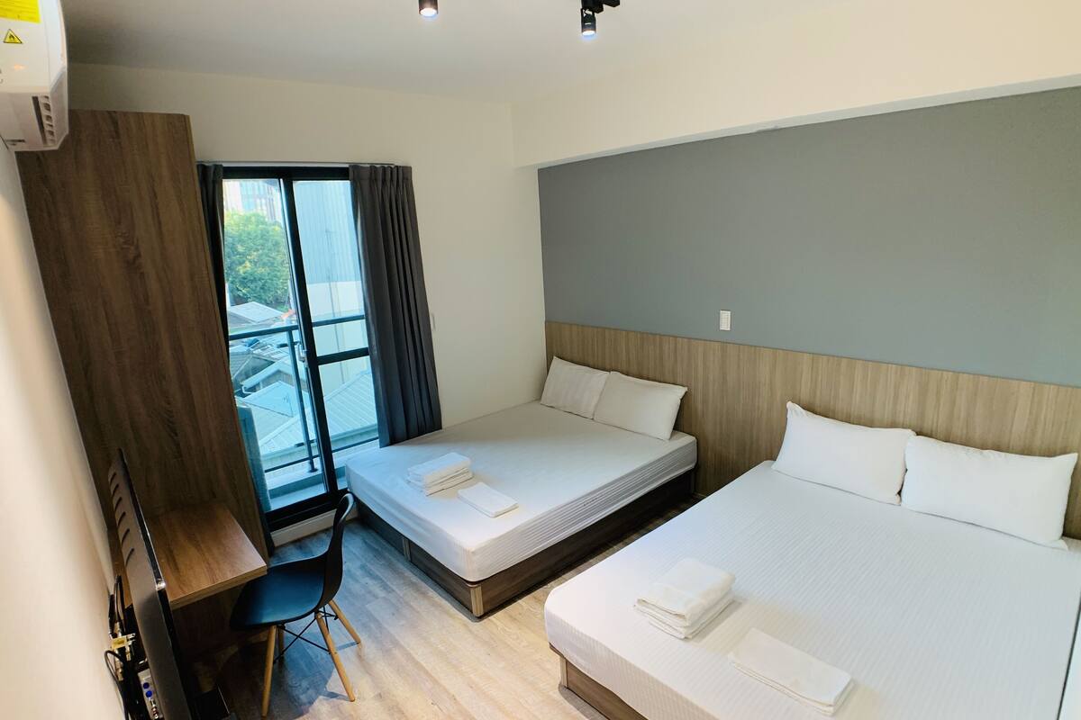 A hotel room with two beds, a desk, and a chair.