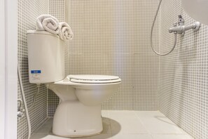 A white toilet with a control panel and a shower head in a tiled bathroom. - OYO 1512 Hotel Harley (Sabang)
