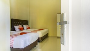 Quarto de hotel com duas camas, cabeceira de madeira e porta branca com puxador prateado.