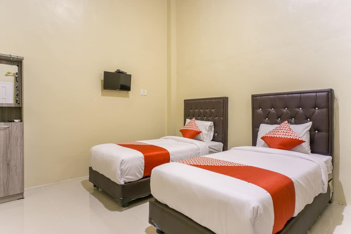 A hotel room with two beds, a TV mounted on the wall, and a wooden cabinet.