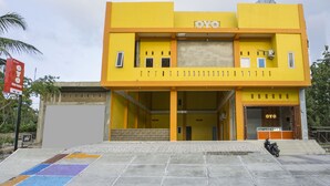 Um edifício de dois andares com fachada amarela e uma placa com a inscrição 'OYO'.