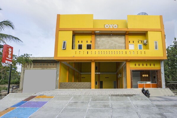 A two-story building with a yellow facade and a sign reading "OYO". - OYO 1512 Hotel Harley (Sabang)