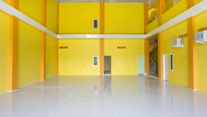 Um átrio espaçoso, com vários níveis, paredes amarelas e pisos de azulejos brancos.
