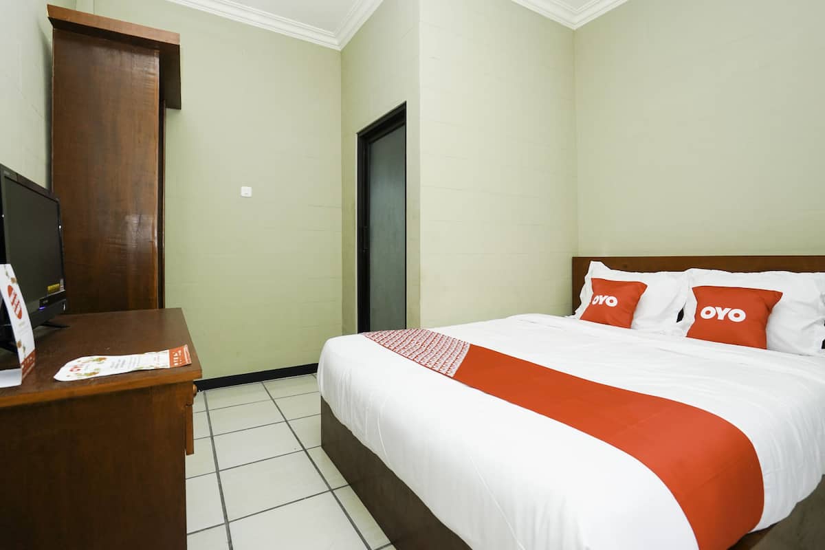 A hotel room with a bed, a desk, and a television.