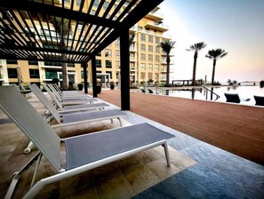 Relax by the pool surrounded by palm trees and enjoy a view of the adjacent water.