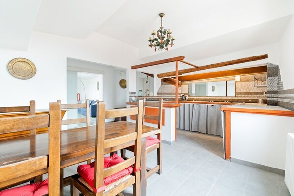 A dining area with wooden furniture and a kitchen in the background.