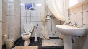 A bathroom with a toilet, bidet, sink, and a shower curtain.
