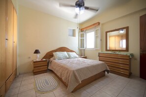 A bedroom with a bed, nightstands, a mirror, a ceiling fan, and a window.