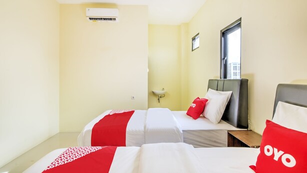Habitación de hotel con dos camas, una ventana, un equipo de aire acondicionado y un lavamanos.
