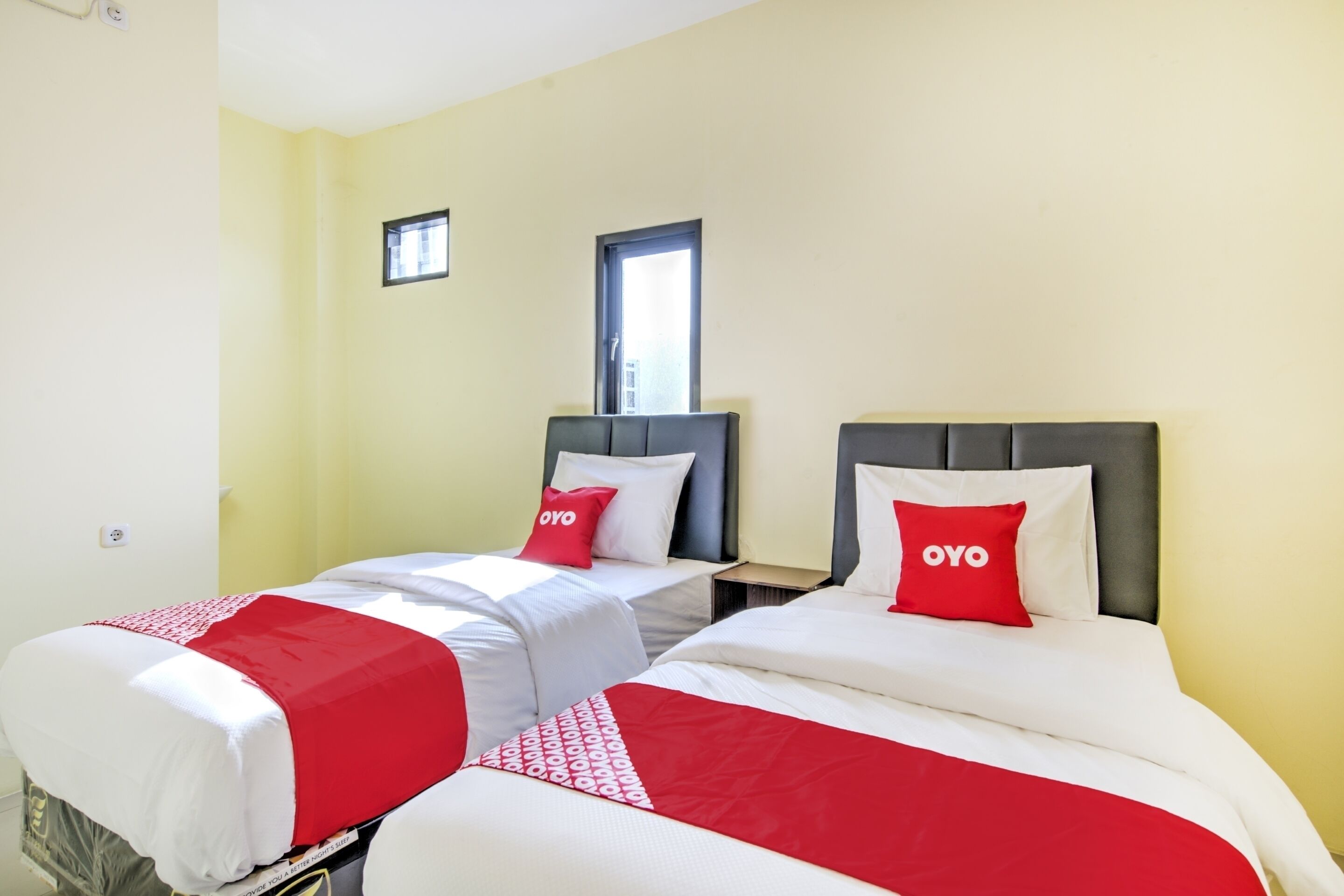 A hotel room with two beds, each with a red and white bedspread and matching pillows.
