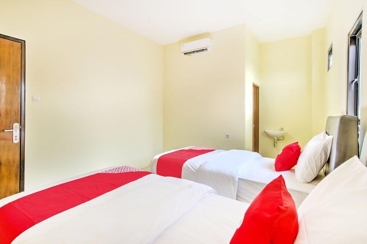 Habitación de hotel con dos camas, una puerta, aire acondicionado de pared y una ventana.