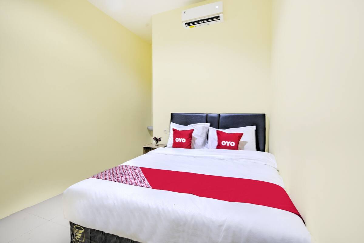 Ein Hotelzimmer mit Bett, Nachttisch und Wand-Klimaanlage.