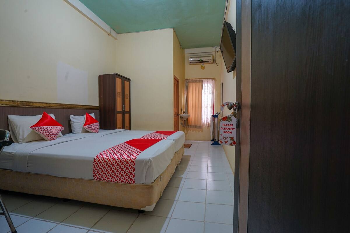 Une chambre d’hôtel avec un lit, une armoire en bois, un téléviseur fixé au mur et une porte avec une pancarte.