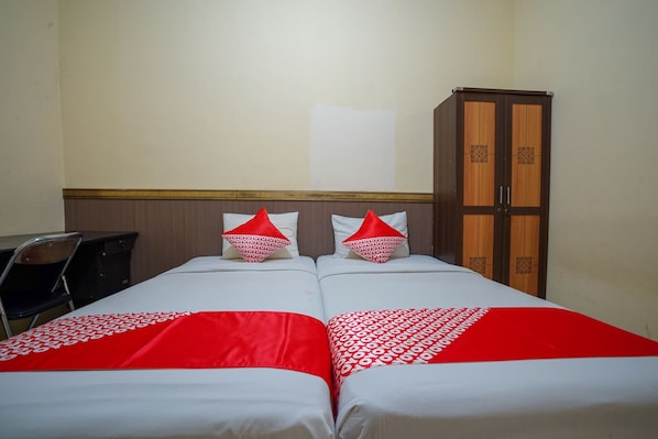 A hotel room with two beds, a desk, and a wardrobe.