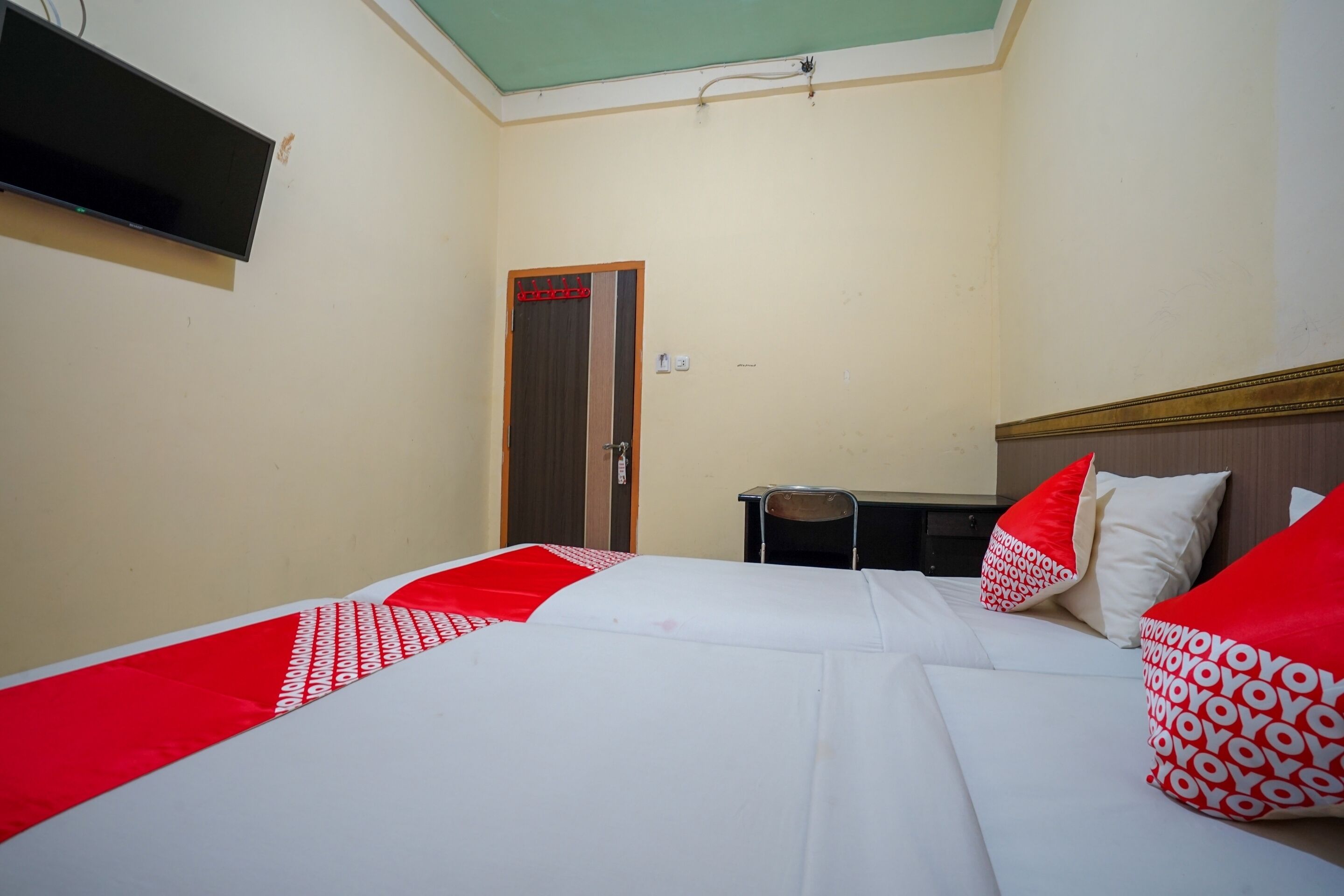 A hotel room with a bed, a desk, and a television mounted on the wall.