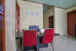 A room with a desk, two red chairs, a computer, and a wall-mounted sign reading "OYO".