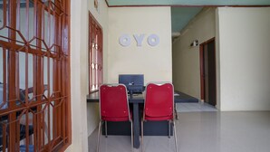 Una habitación con dos sillas rojas, un escritorio con una computadora y una pared con las letras 'OYO'.